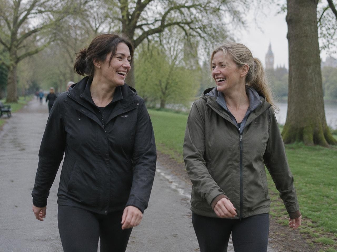 Two friends laughing on a brisk walk through a London park